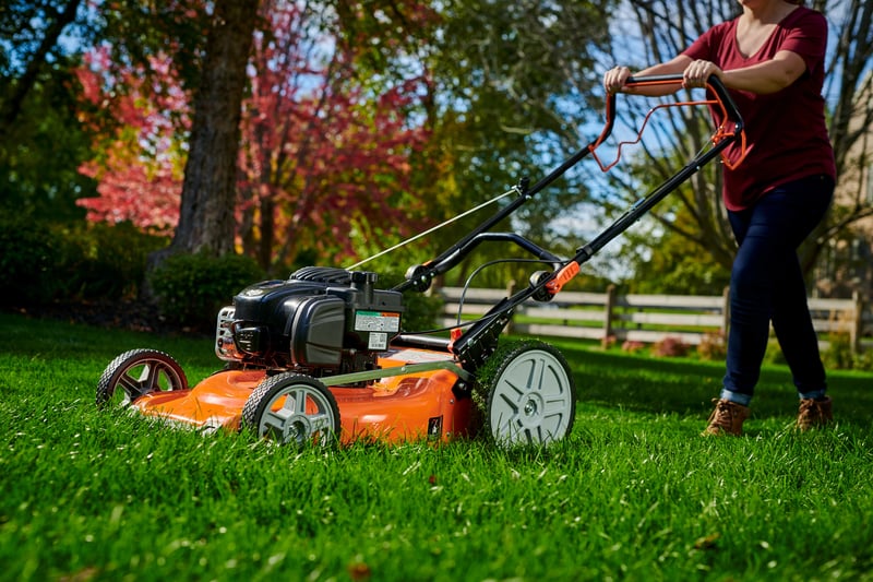 Woman mowing her lawn with a Briggs & Stratton-Powered walk behind lawn mower.
